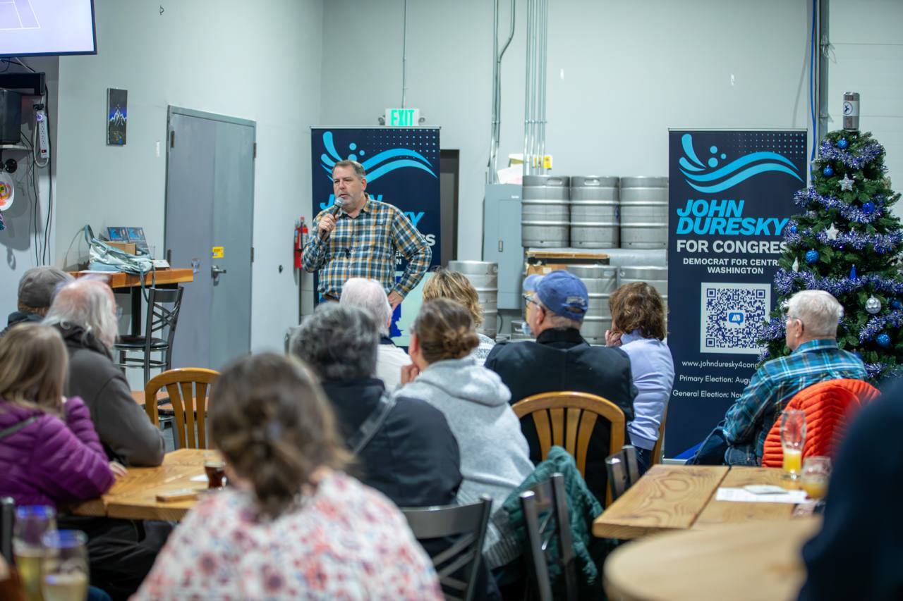 John speaking to a full room at a brewery town hall